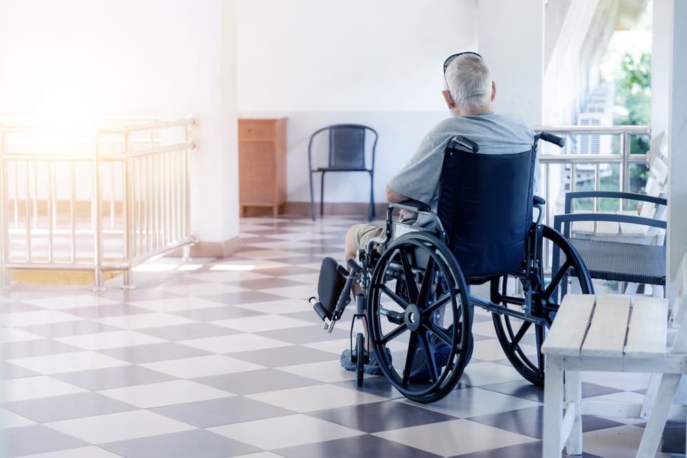 Lonely male elderly sitting in a wheelchair at Elderly care facility to wait for visitors.